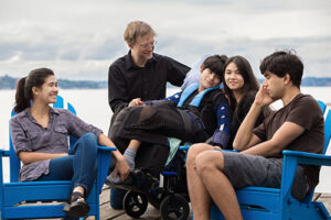 Multiethnic family with son in wheelchair, relaxing by the lake